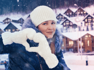 A girl with winter clothes making a heart